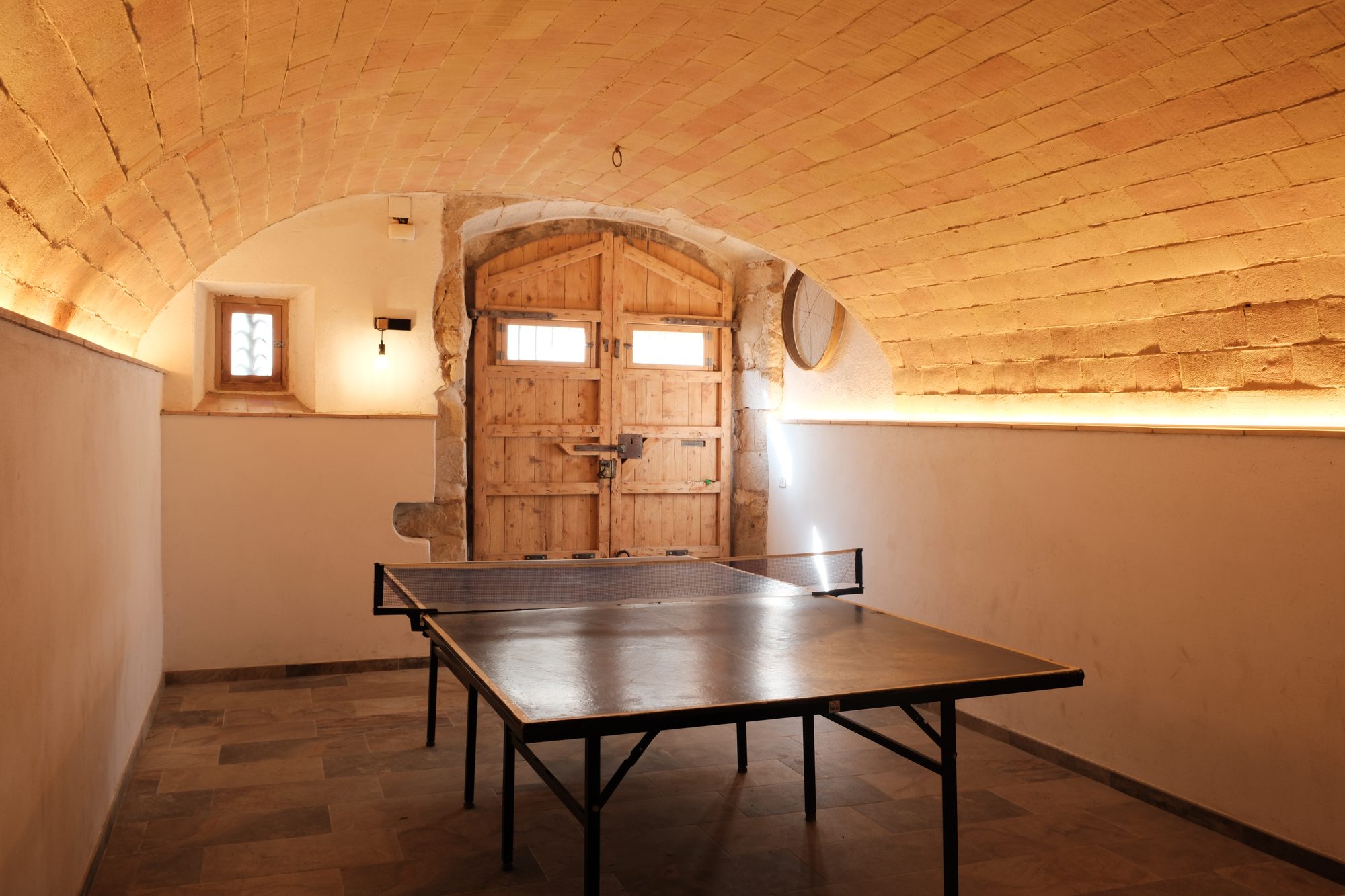 Sala de jocs de Can Joan Empordà sota volta de pedra, amb taula de ping-pong