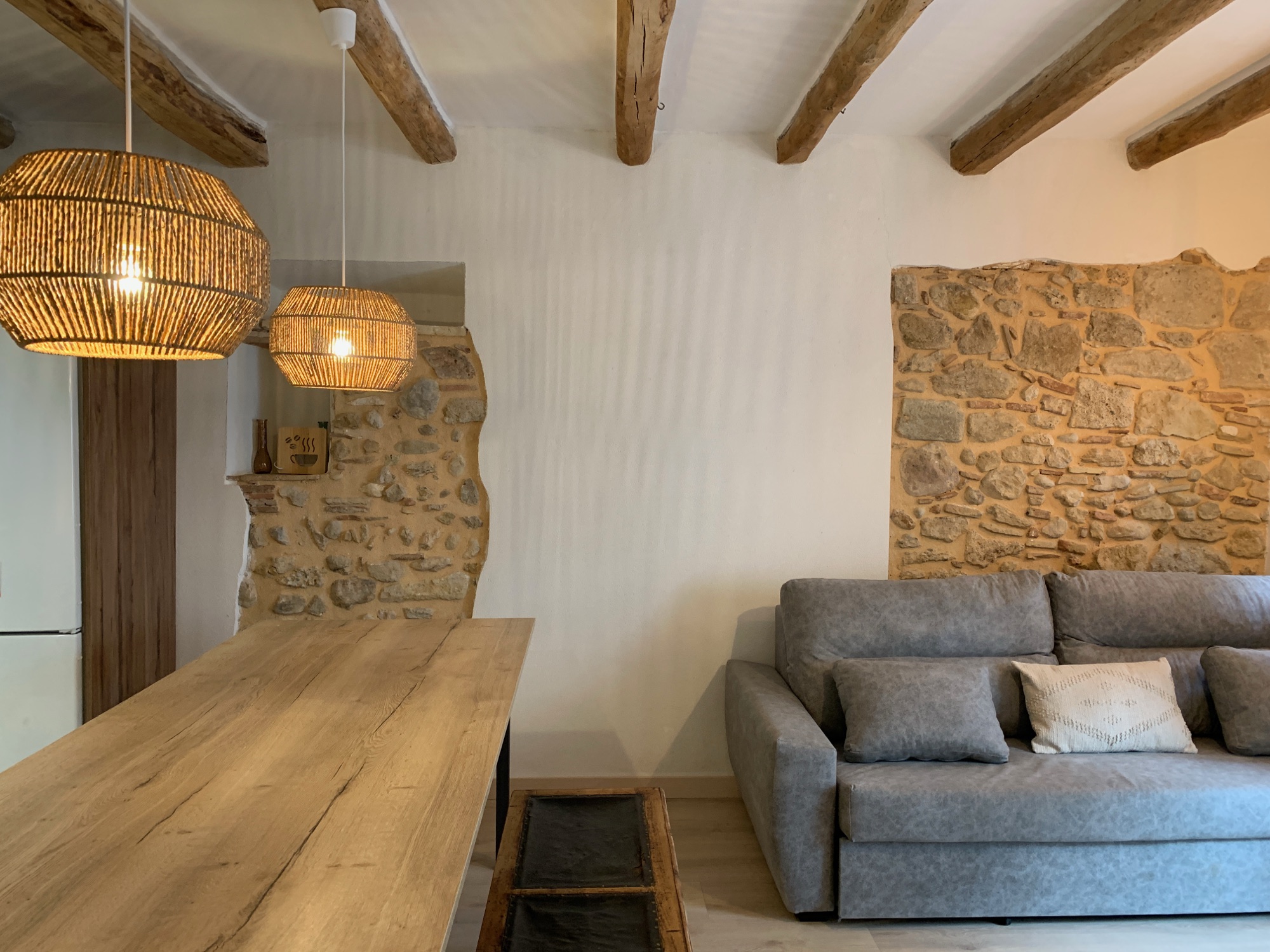 Sala d'estar de Can Joan Empordà amb bigues de fusta i pedra vista
