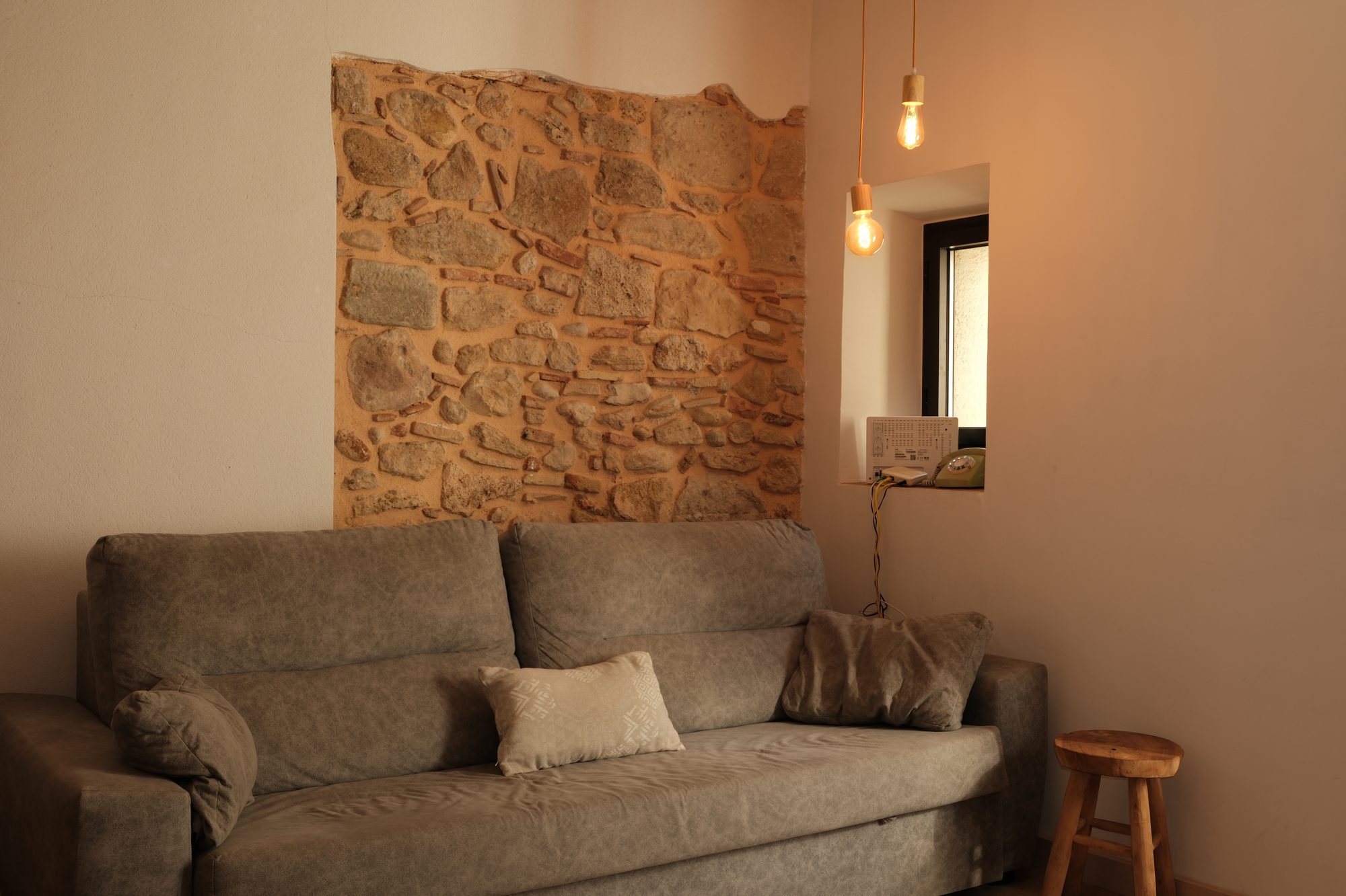 Sofà de la sala d'estar de Can Joan Empordà davant el mur de pedra